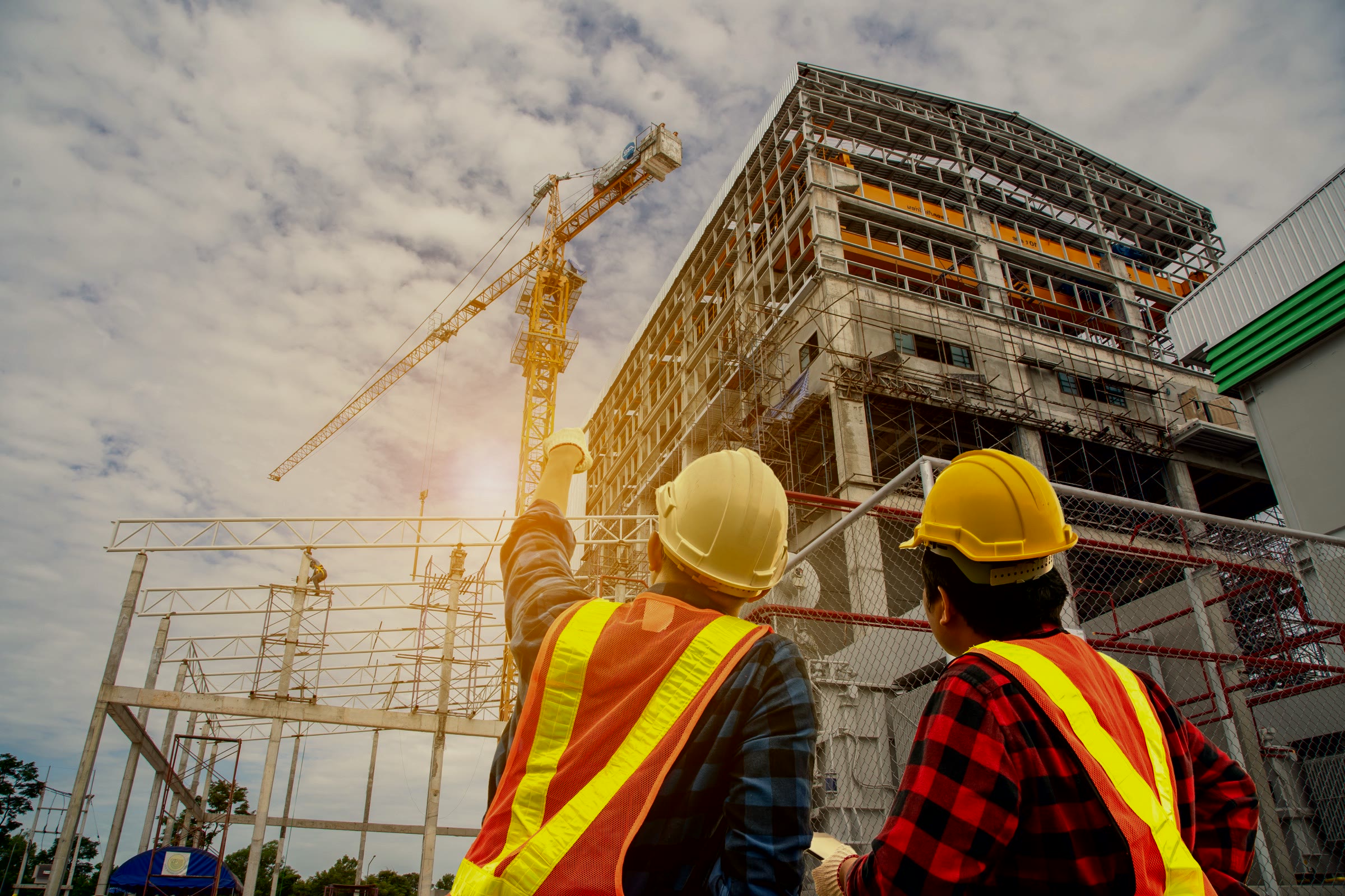 Construction workers reviewing a commercial building project with a tower crane
